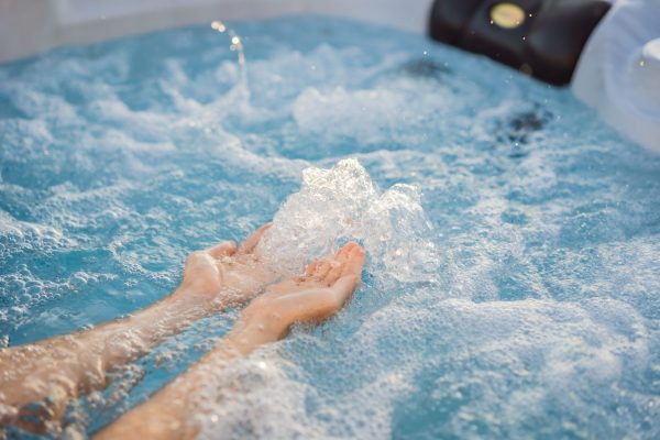 Portrait of young carefree happy smiling woman relaxing at hot tub during enjoying happy traveling moment vacation life against the background of green big mountains.